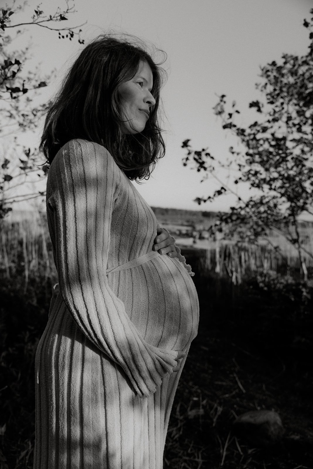 Nainen pitelee omaa raskausvatsaansa sivukuvassa. Kuvannut raskausajankuvaaja Heidi Väisänen.