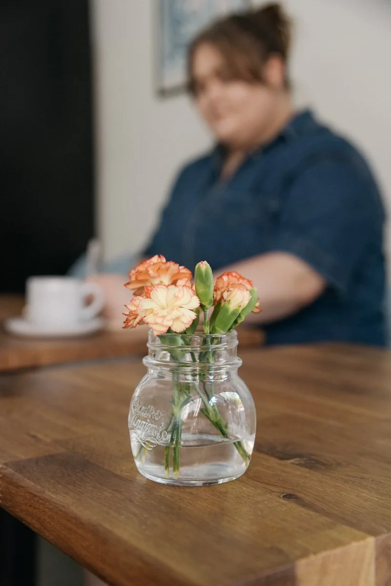 Yrityskuvaus helsinkiläisessä kahvilassa. Taustalla yrittäjä juo kahvia. Kuvannut brändikuvaaja Heidi Väisänen.