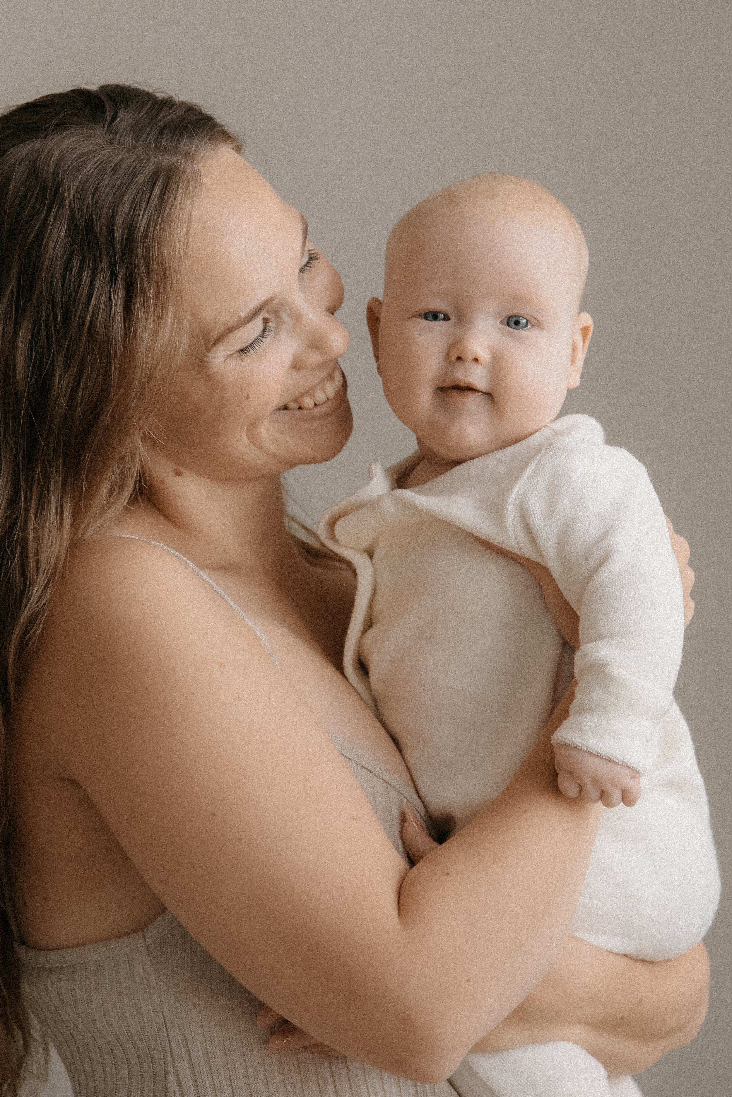 Äidin ja lapsen valokuvaus valoisalla studiolla. Lapsi äidin sylissä.