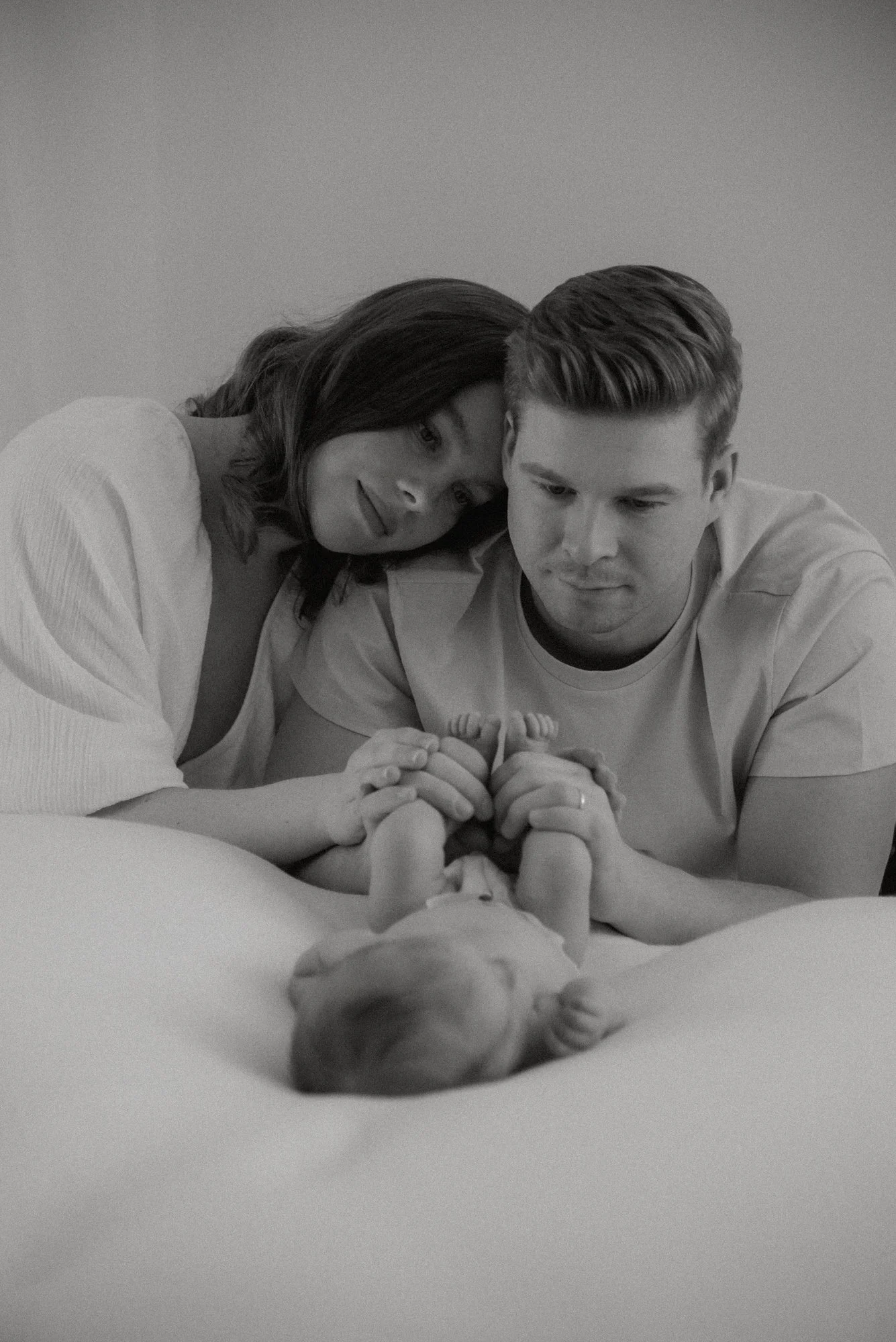 Ylpeät vanhemmat katsovat pienokaistaan. Vauvakuvaus studiolla.