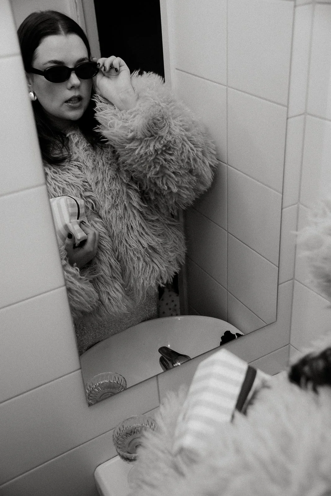 Edlan brändikuvaus, yrittäjä katsoo itseään peilistä brändin meikkipussi kainalossaan.