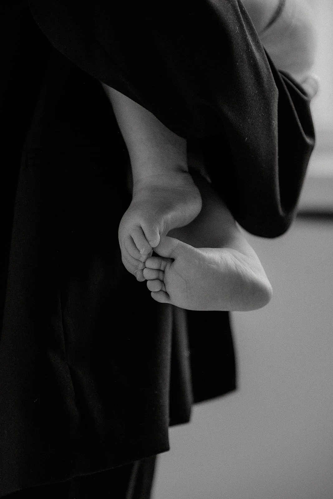 Vauva äidin sylissä, vauvalla varpaat kippuralla. Kuvannut äiti- ja lapsikuvauksessa Heidi Väisänen.