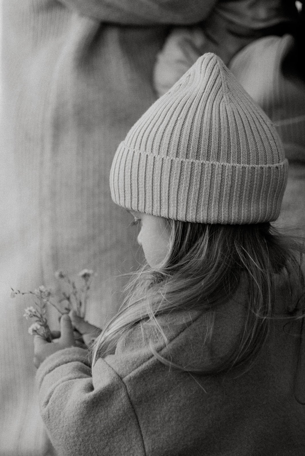 Pieni lapsi kukkia kädessää mustavalkokuvassa.