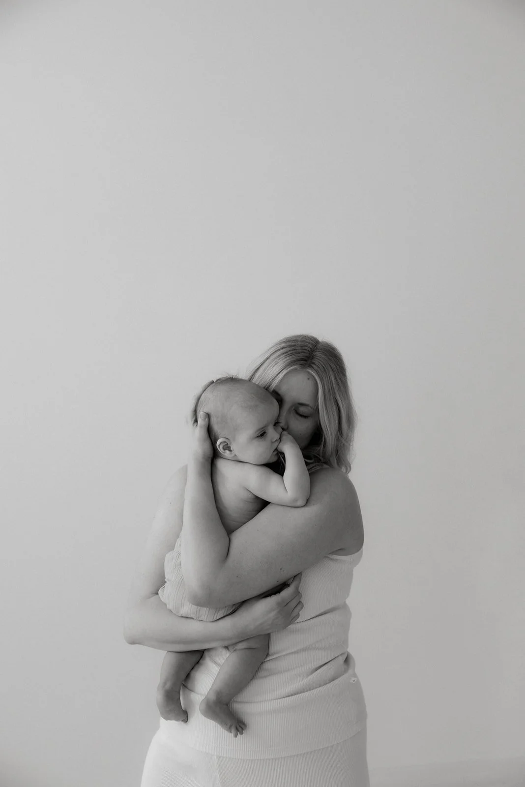 Äiti- ja lapsikuvaus, äiti halaa vauvaa sylissään.