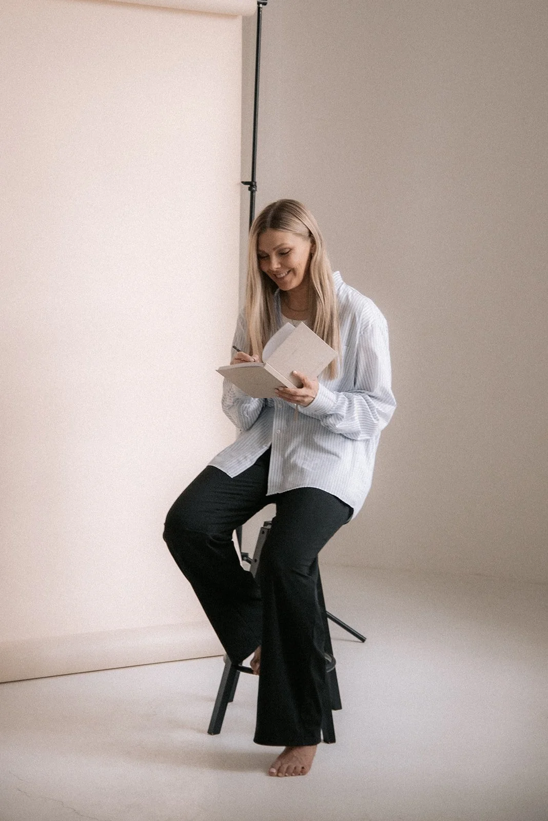 Naisyrittäjä kirjoittaa muistikirjaansa Heidi Väisäsen valoisassa studiossa.