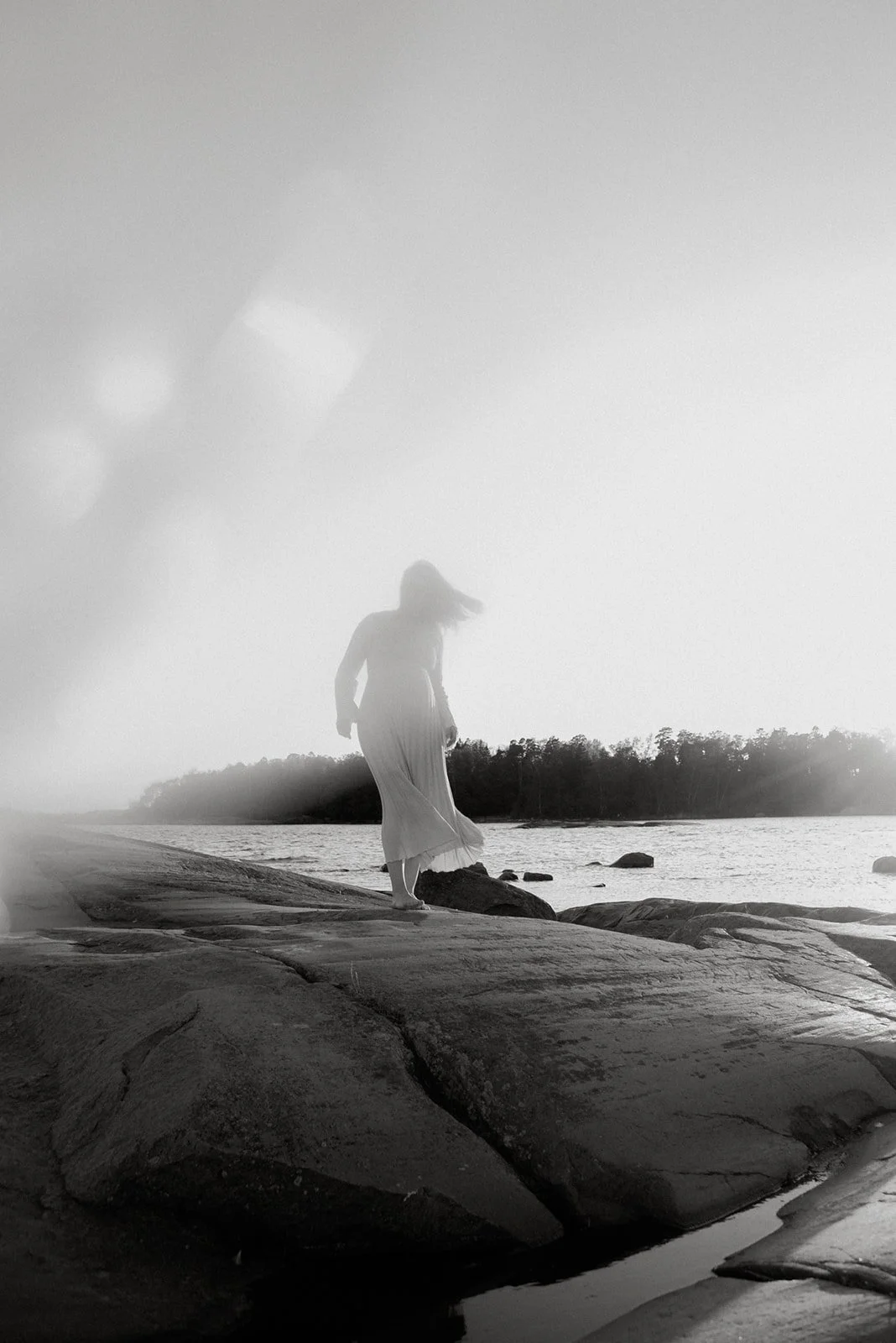 Odotuskuva luonnossa. Odottava äiti kävelee kallioilla meren äärellä.