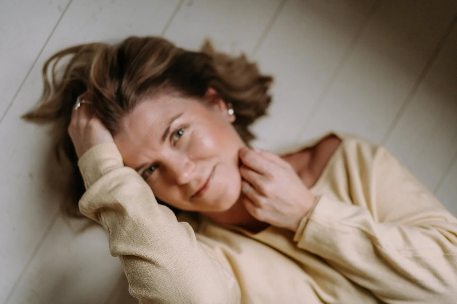 Valokuvaaja Heidi Väisänen makaa selällään lattialla ja katsoo kameraan