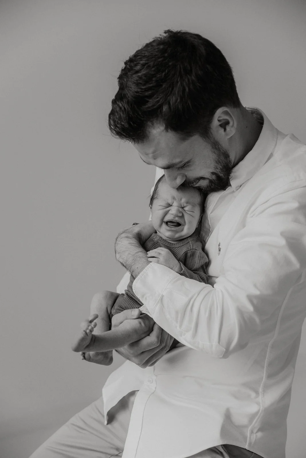 Itkevä vauva isänsä rauhoittelevassa sylissä. Vauvan ensihetket on ikuistanut valokuvaaja Heidi Väisänen.