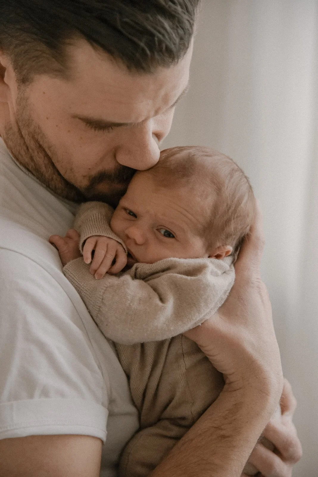 Vauva turvallisesti isänsä sylissä. Vauvakuvaus studiolla.