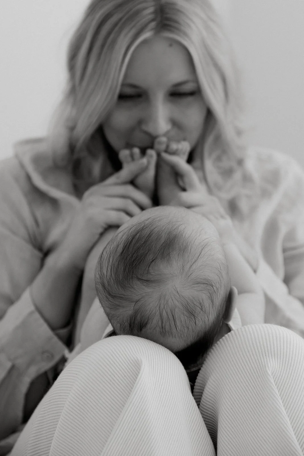 Äiti suukottaa vauvan varpaita hellästi. Äiti- ja lapsikuvaus Heidi Väisäsen taltioimana.