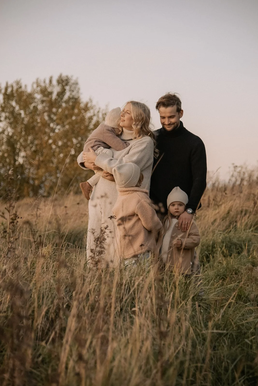 Idyllinen perhekuva luontomaisemassa kauniissa iltavalossa.