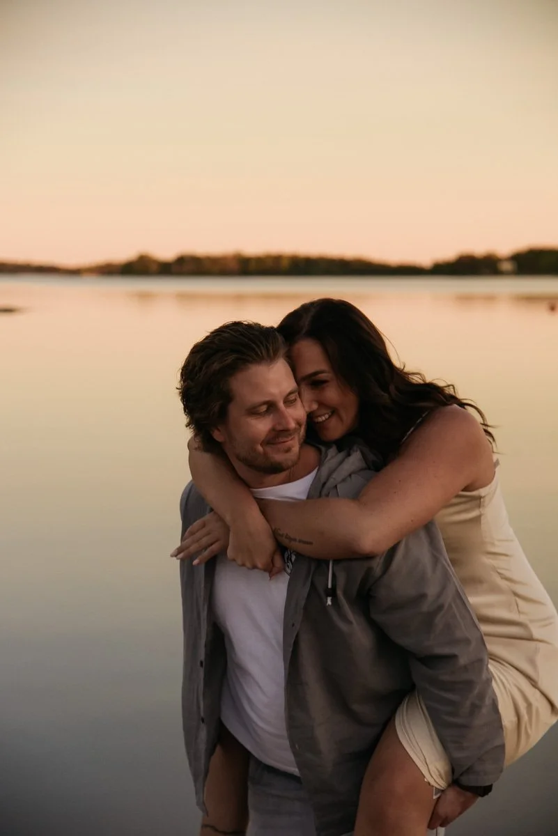Onnellinen pariskunta tyynen järven rannalla ilta-auringossa. Pariskuntakuvaus Espoo.