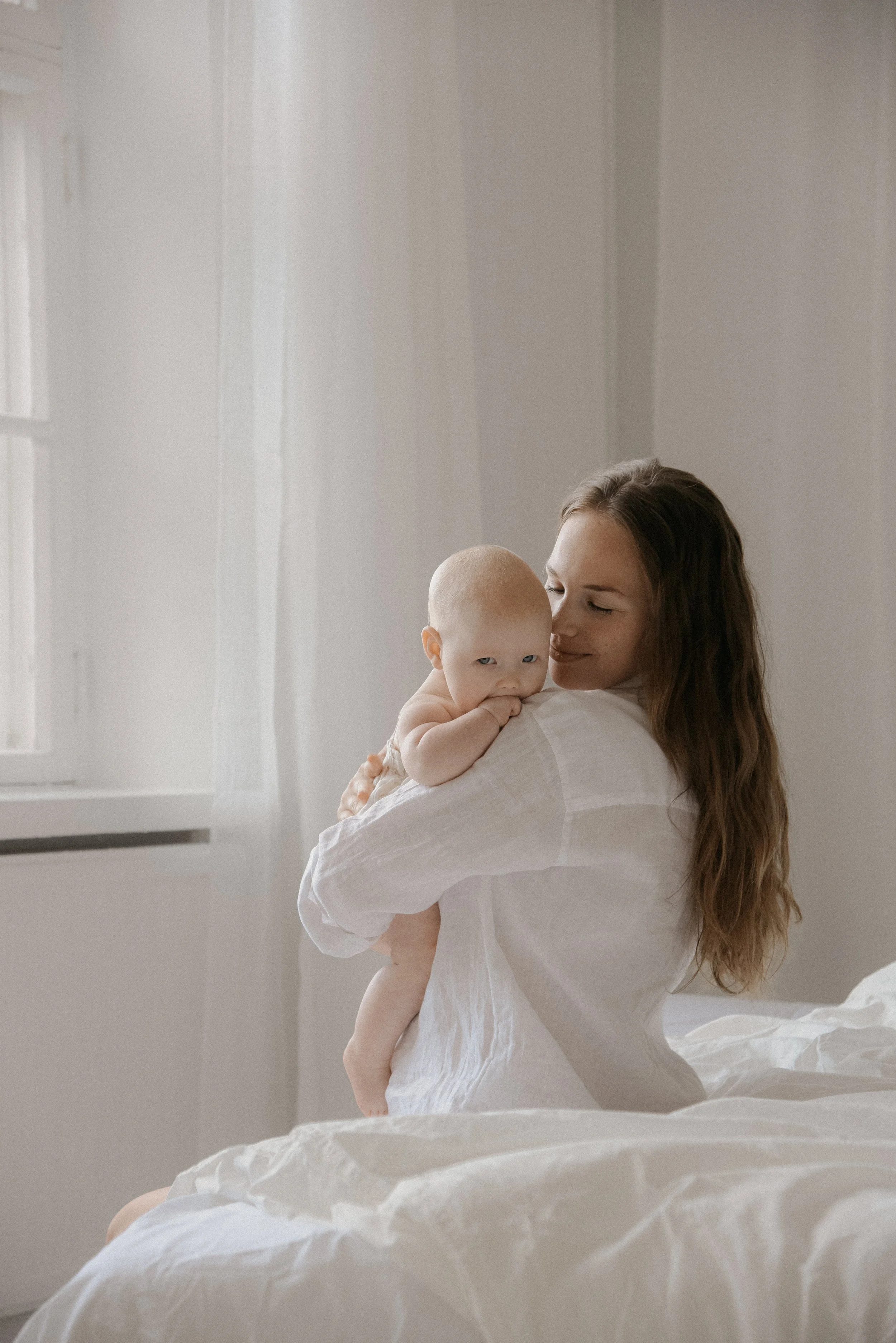 Äiti pitelee lastaan sylissä. Äiti-lapsikuvaus studiolla.
