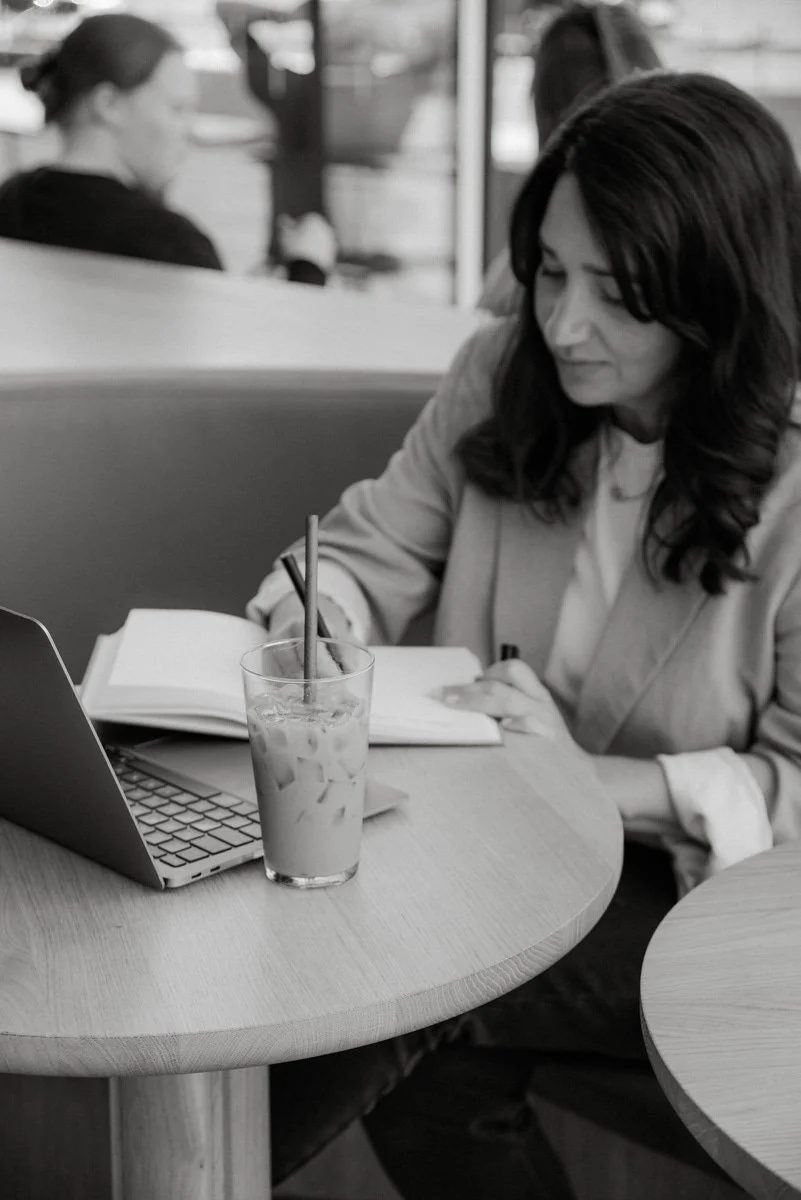 Mustavalkoinen yrityskuva jossa yrittäjä kirjoittaa muistivihkoonsa.