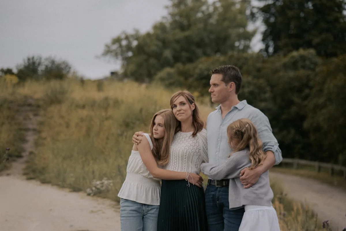 Perhekuvaus luonnossa, äiti, isä ja kaksi lasta halaa toisiaan. Kuvannut valokuvaaja Heidi Väisänen.