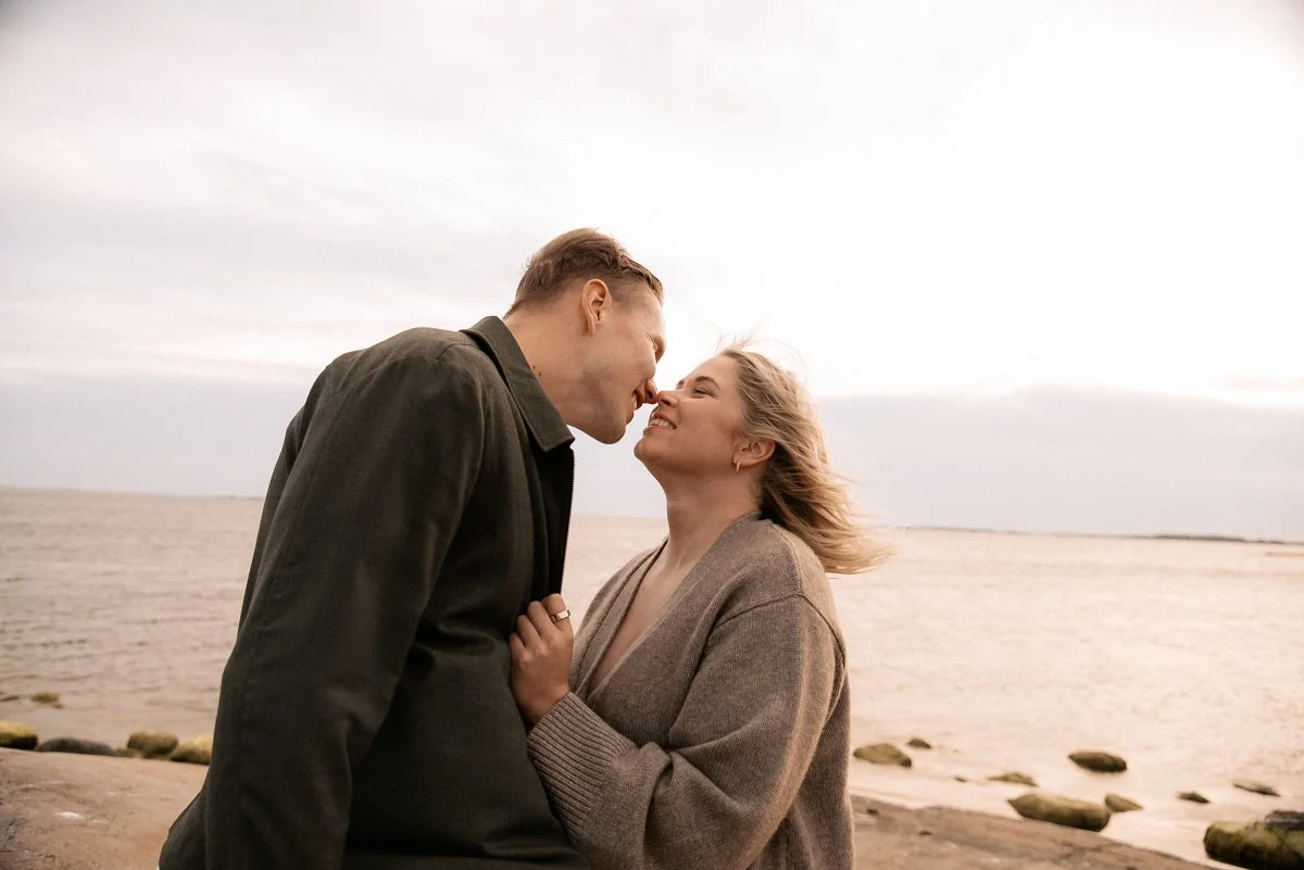 Ilta-auringossa toteutettu odotuskuvaus, parikunta läheisissä tunnelmissa meren rannalla.