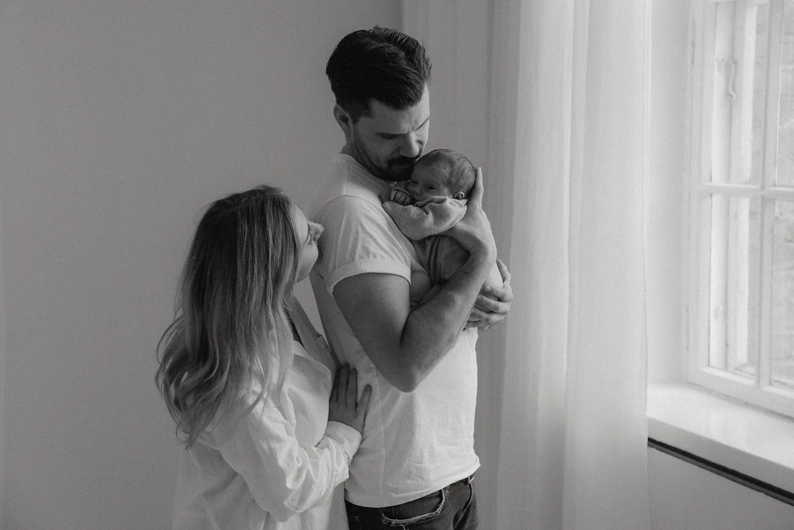 Perhe ison ikkunan edessä vanhalla studiolla Keravalla.