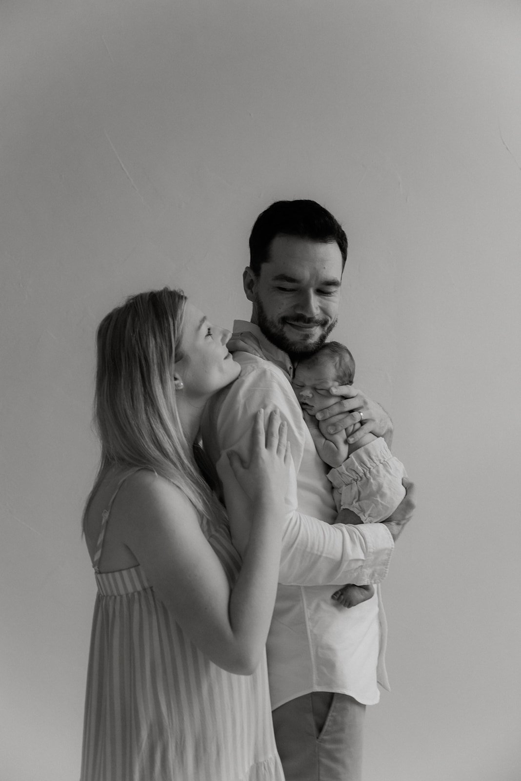 Pieni vastasyntynyt vauva isän ja äidin hellässä syleilyssä. Vauvakuvaus Helsinki.