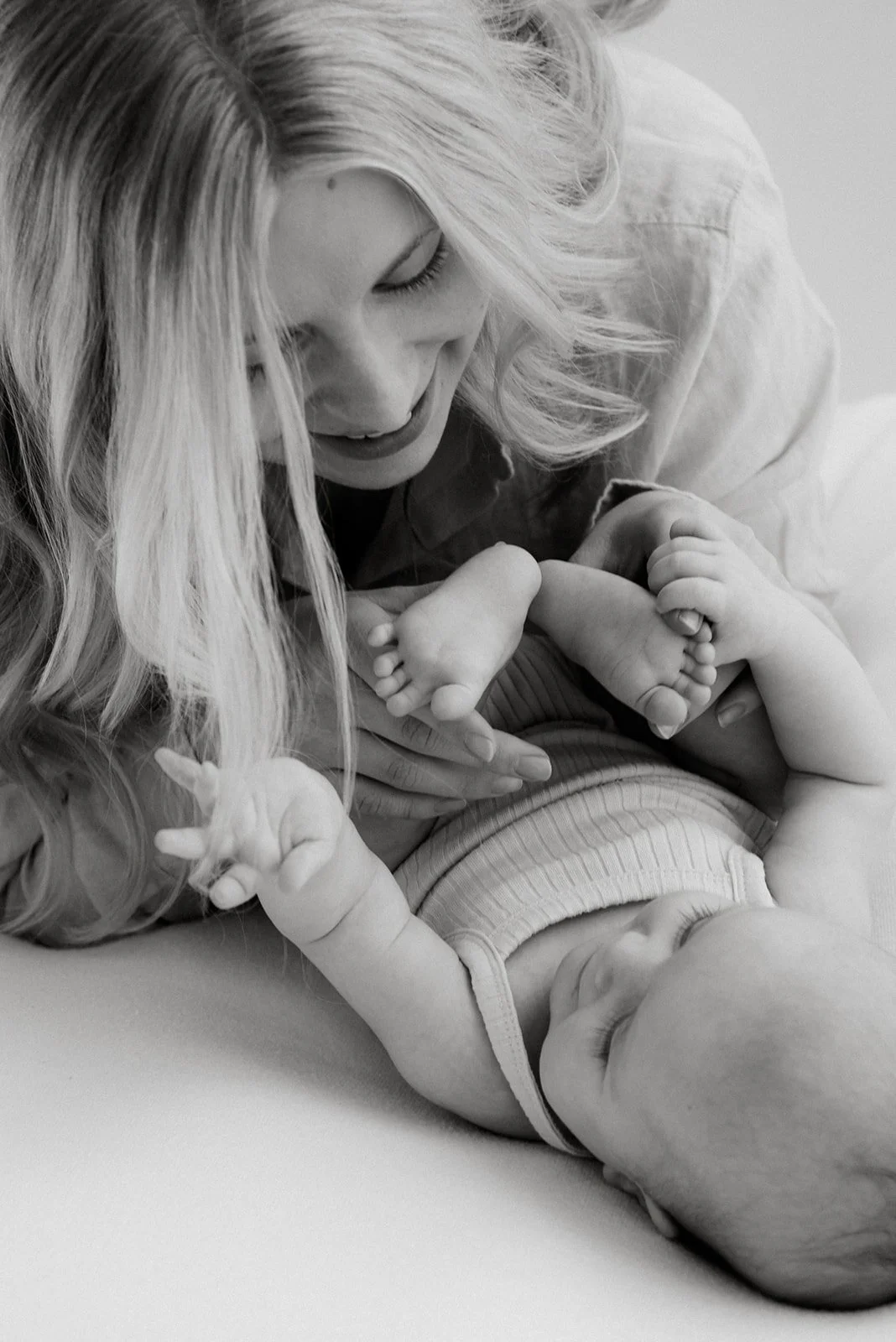 Lähikuvassa äiti pitelee lapsen varpaita käsissään. Äiti- ja lapsikuvaus Heidi Väisäsen studiolla.