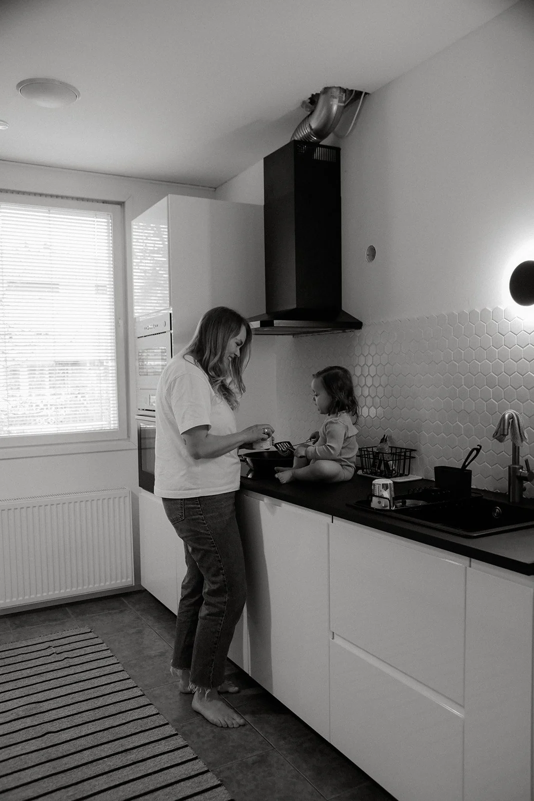 Äiti ja lapsi leikkivät kotinsa keittiössä. Perhekuvaus kotioloissa, kuvaaja Heidi Väisänen.