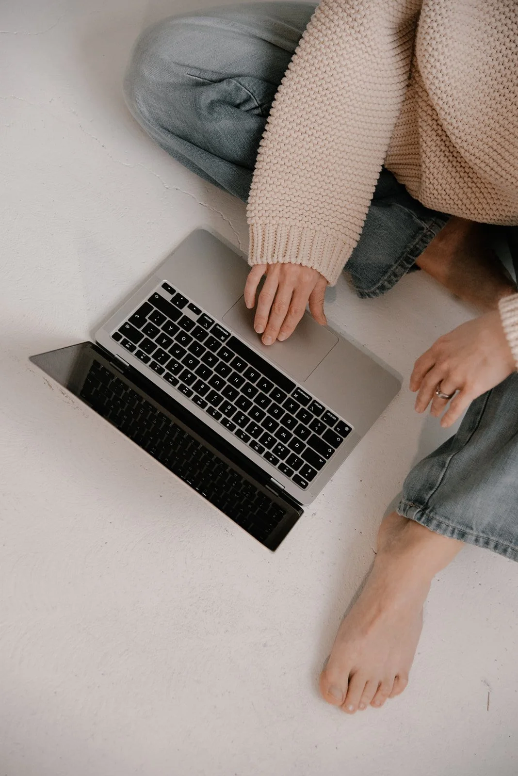 Vaumiin brändikuvaus, yrittäjä istuu farkuissa lattialla ja naputtelee tietokonetta.