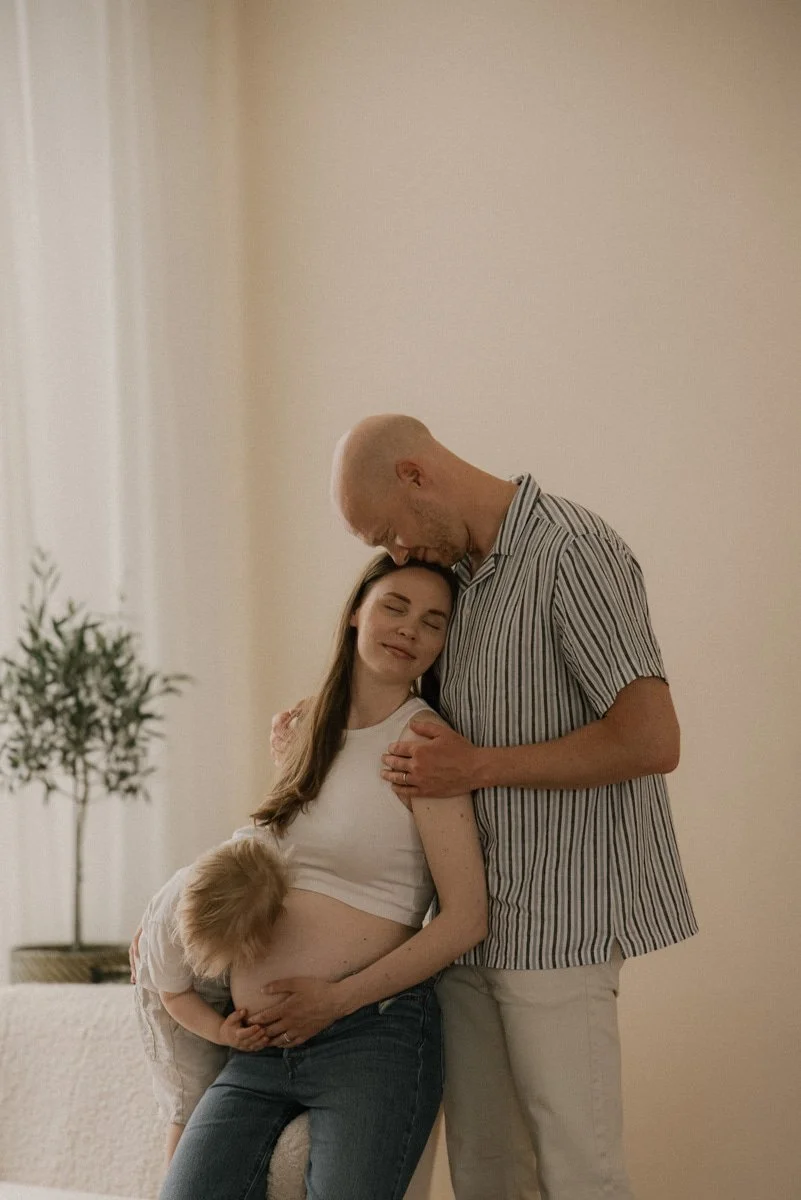 Raskaana oleva äiti, lapsi ja isä. Rauhallinen ja lempeä perheen välinen hetki.