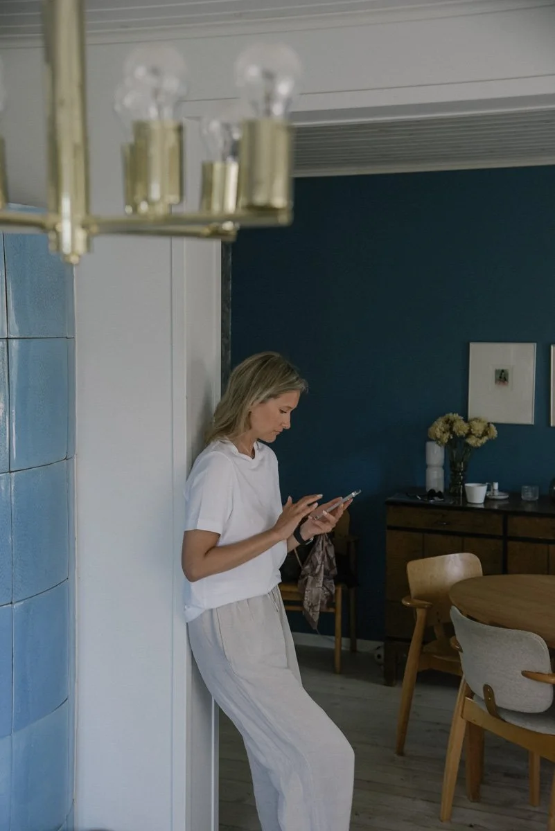 Neam Societyn brändikuvaus, yrittäjä nojaa seinään ja näppäilee kännykkää.