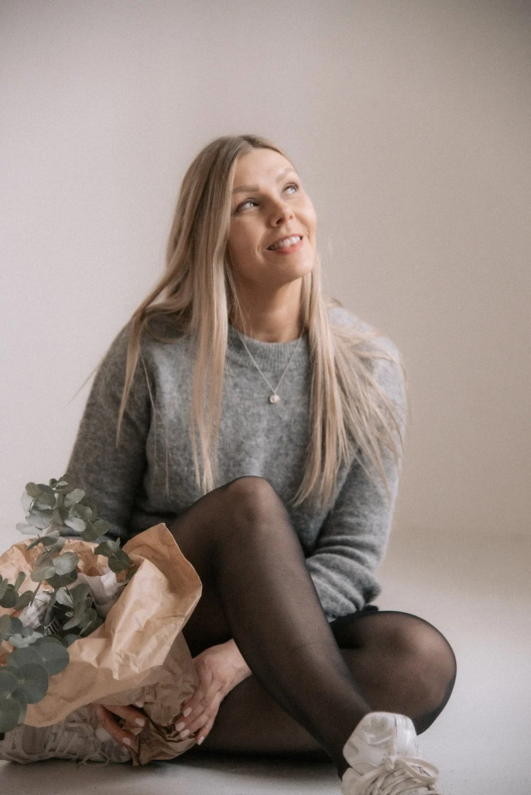 Heartiven brändikuvaus, yrittäjä Terhi Lahti istuu Heidi Väisäsen studion lattialla kukkakimppu käsissään.