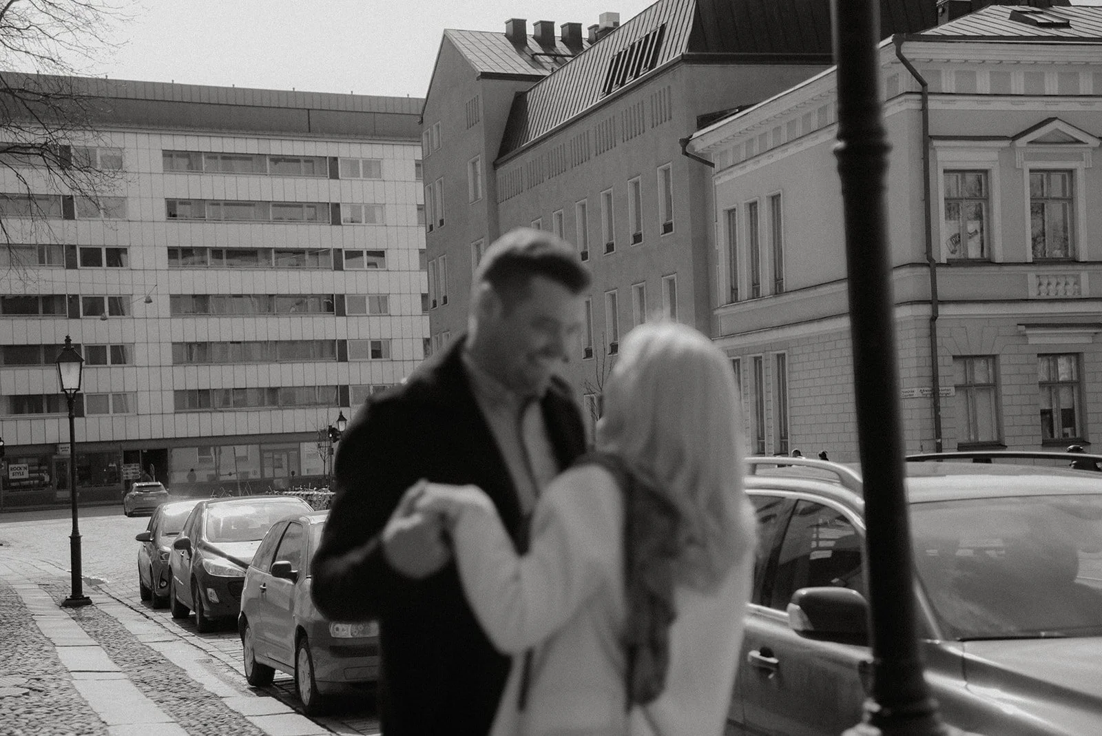 Pariskunta katsoo toisiaan silmiin katumaisemassa. Pariskuntakuvaus Helsinki.