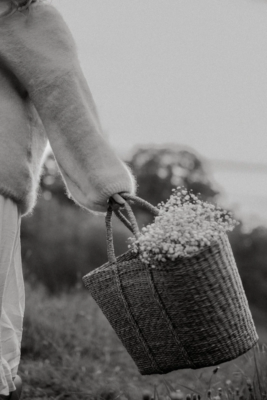 Mustavalkoinen brändikuva, jossa doula Jutta Alanenen kantaa kukkia kassissa.