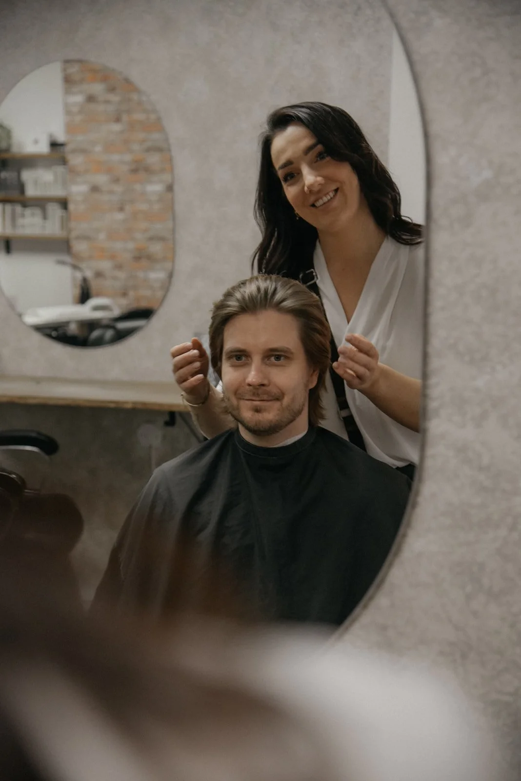 Kampaaja leikkaa miehen hiuksia. Kuvannut yrityskuvaaja Heidi Väisänen.