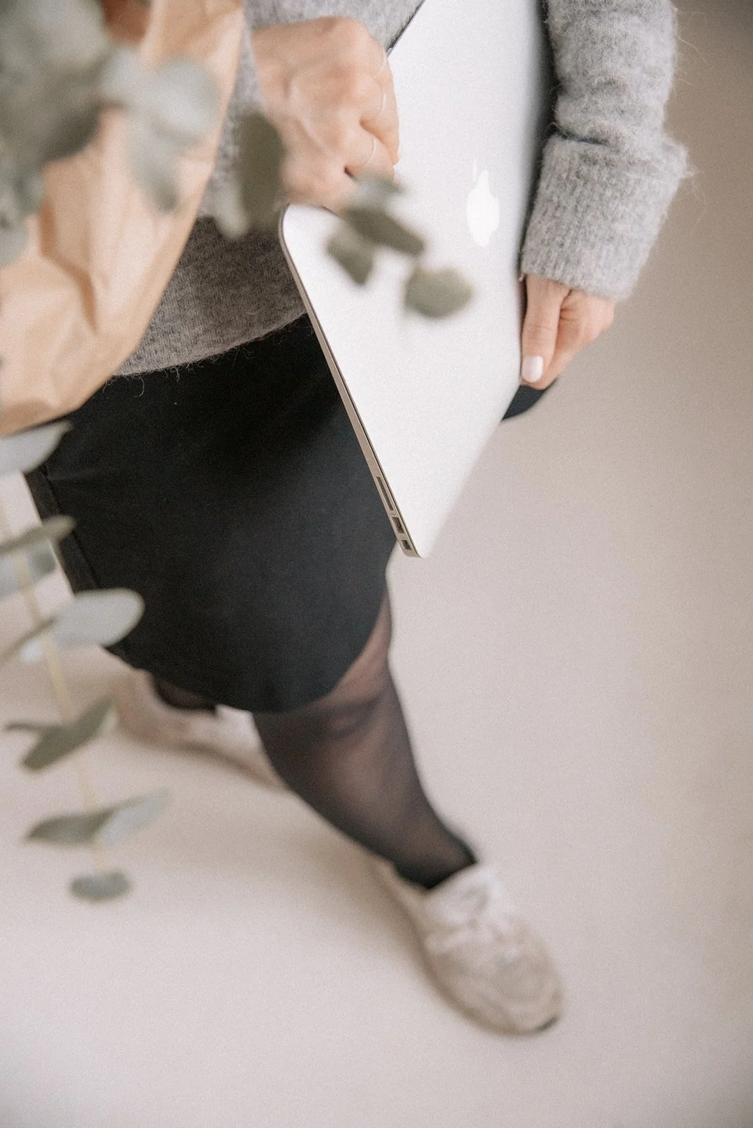 Heartiven yrityskuvaus Heidi Väisäsen studiolla. Yrittäjä kantaa tietokonetta ja kukkakimppua.