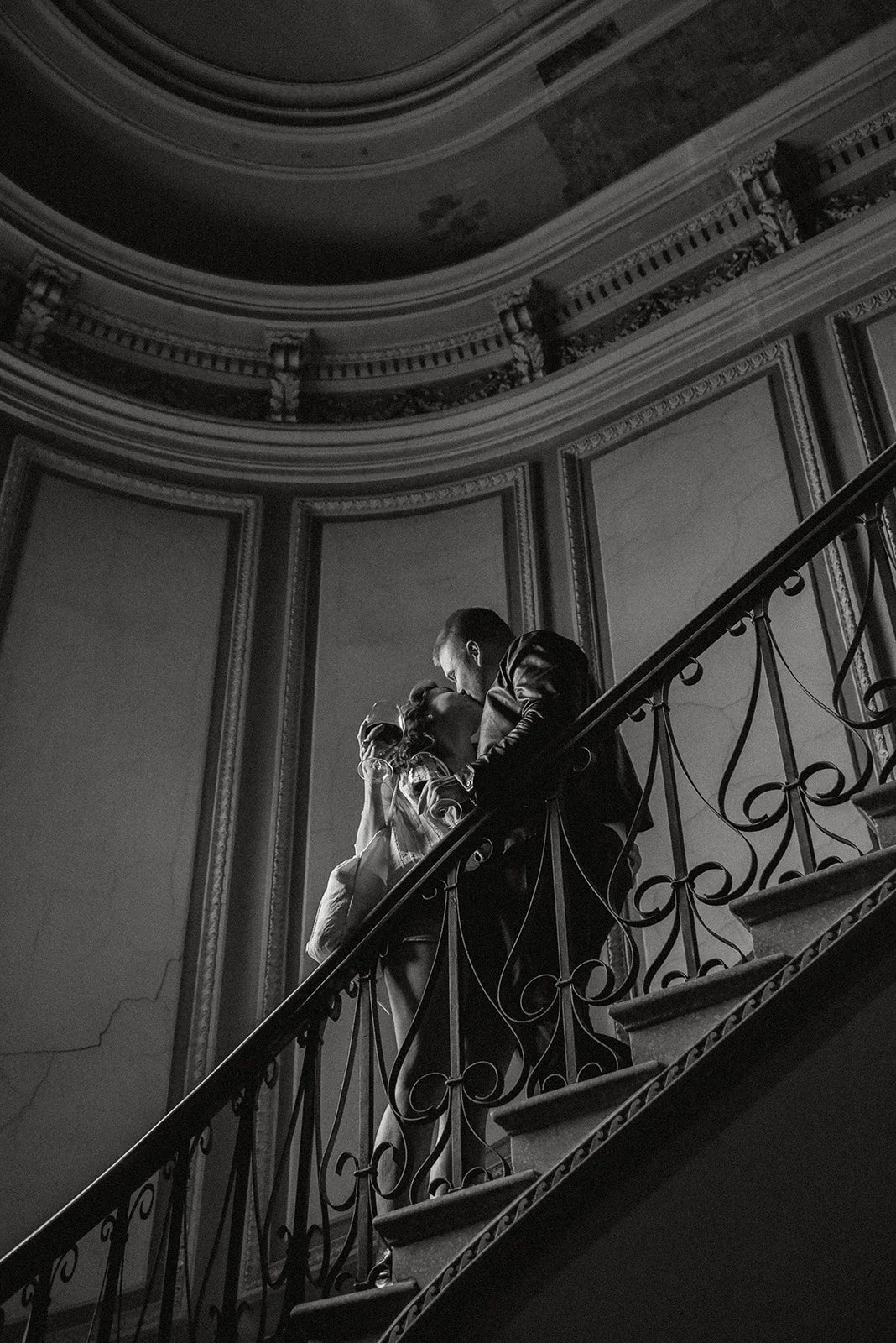 Mustavalkokuva, jossa pariskunta suutelee portaikoissa. Pariskuntakuvaus Helsinki.