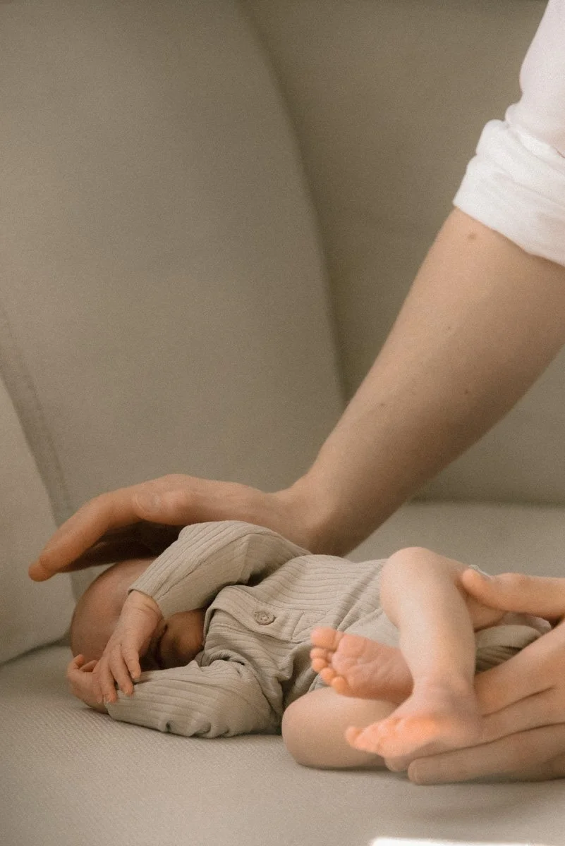 Pieni vauva makoilee sohvalla hellässä kosketuksessa. Vauvakuvaus kotona.