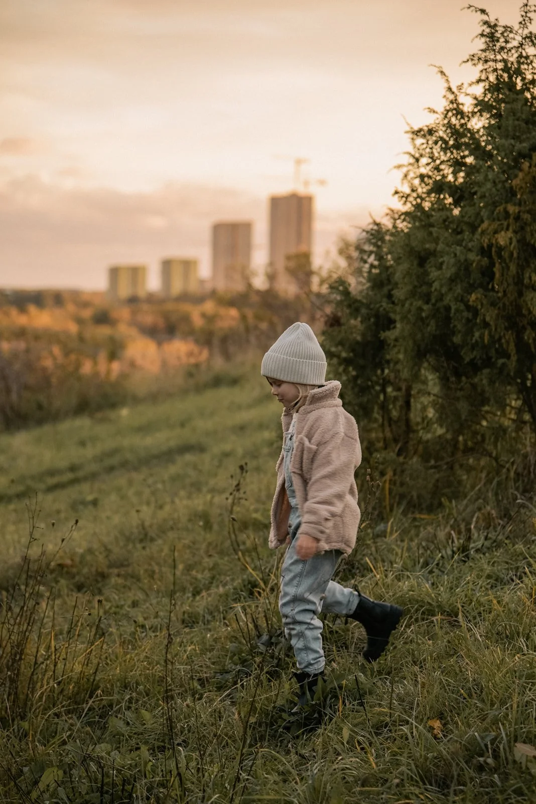 Perhekuvaus, pieni tyttö astelee nurmikolla, taustalla Helsingin siluetti