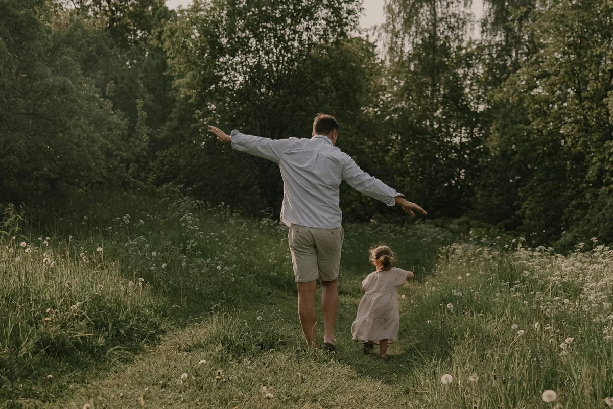 Perhekuvaus Espoo, isä ja lapsi kävelevät vehreässä luontomaisemassa.