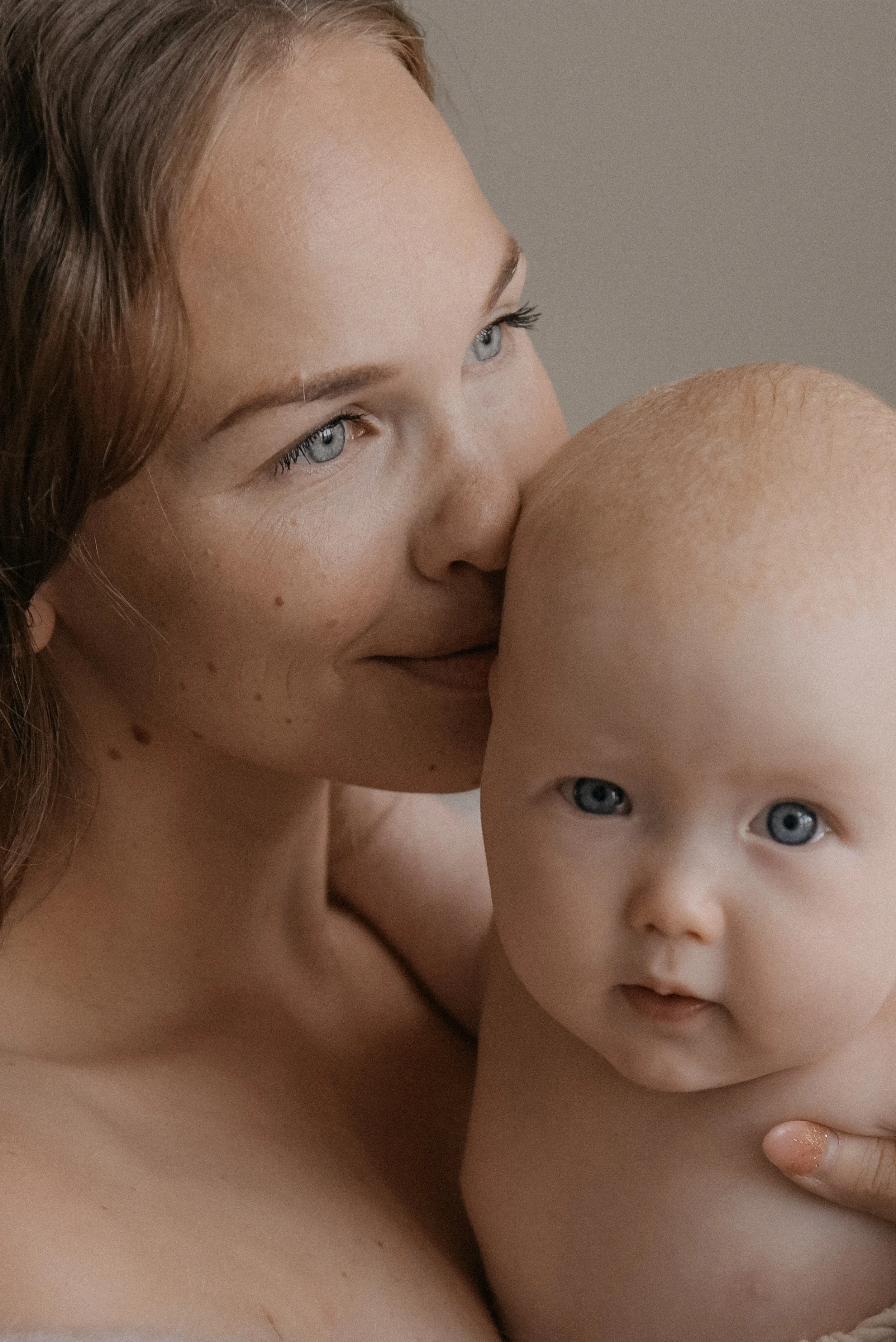 Äiti syleilee lastaan valoisassa kuvassa. Kuvannut vauvakuvaaja Heidi Väisänen.