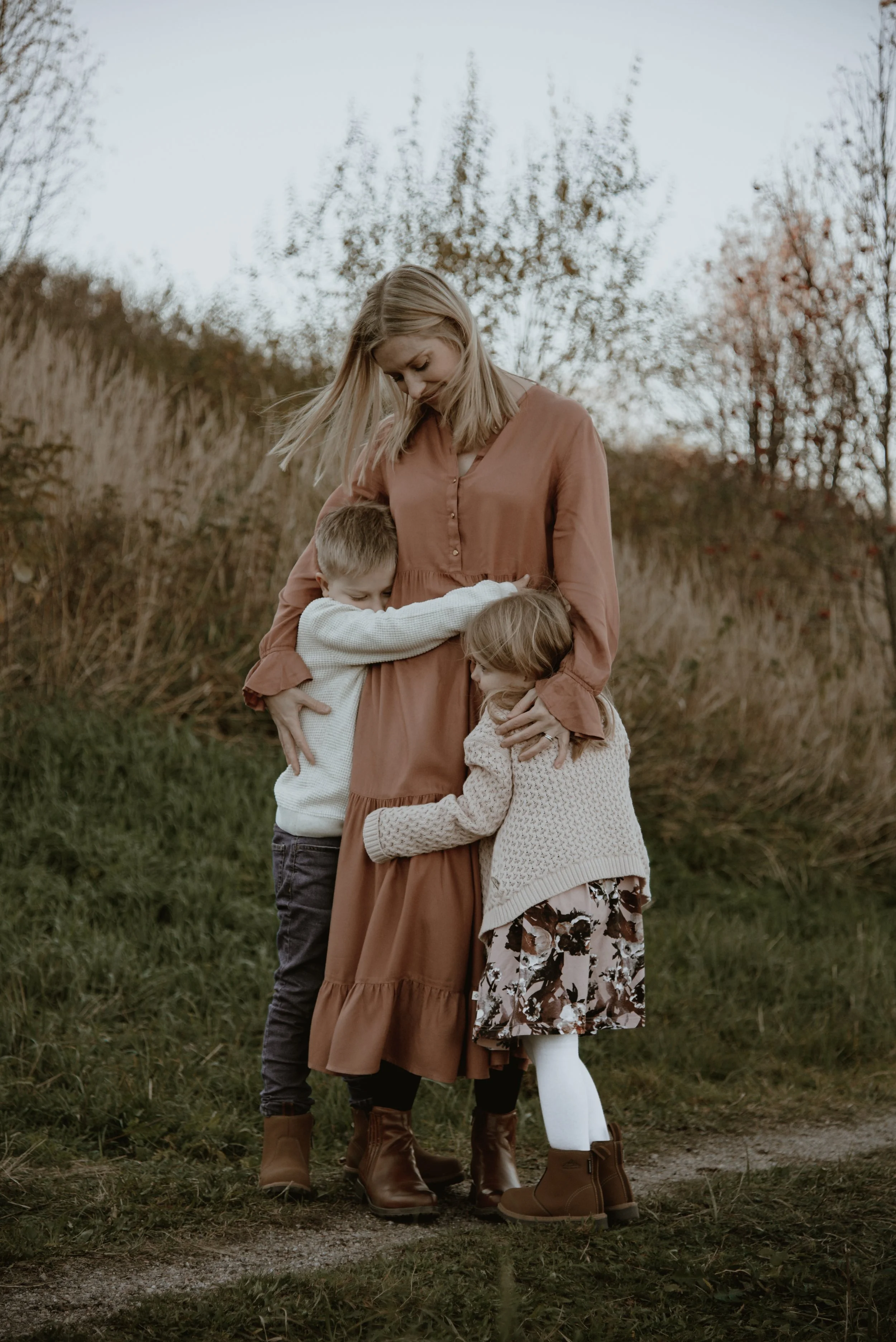 Perhekuvaus miljöössä, äiti ja kaksi lasta halaavat. Kuvannut valokuvaaja Heidi Väisänen.