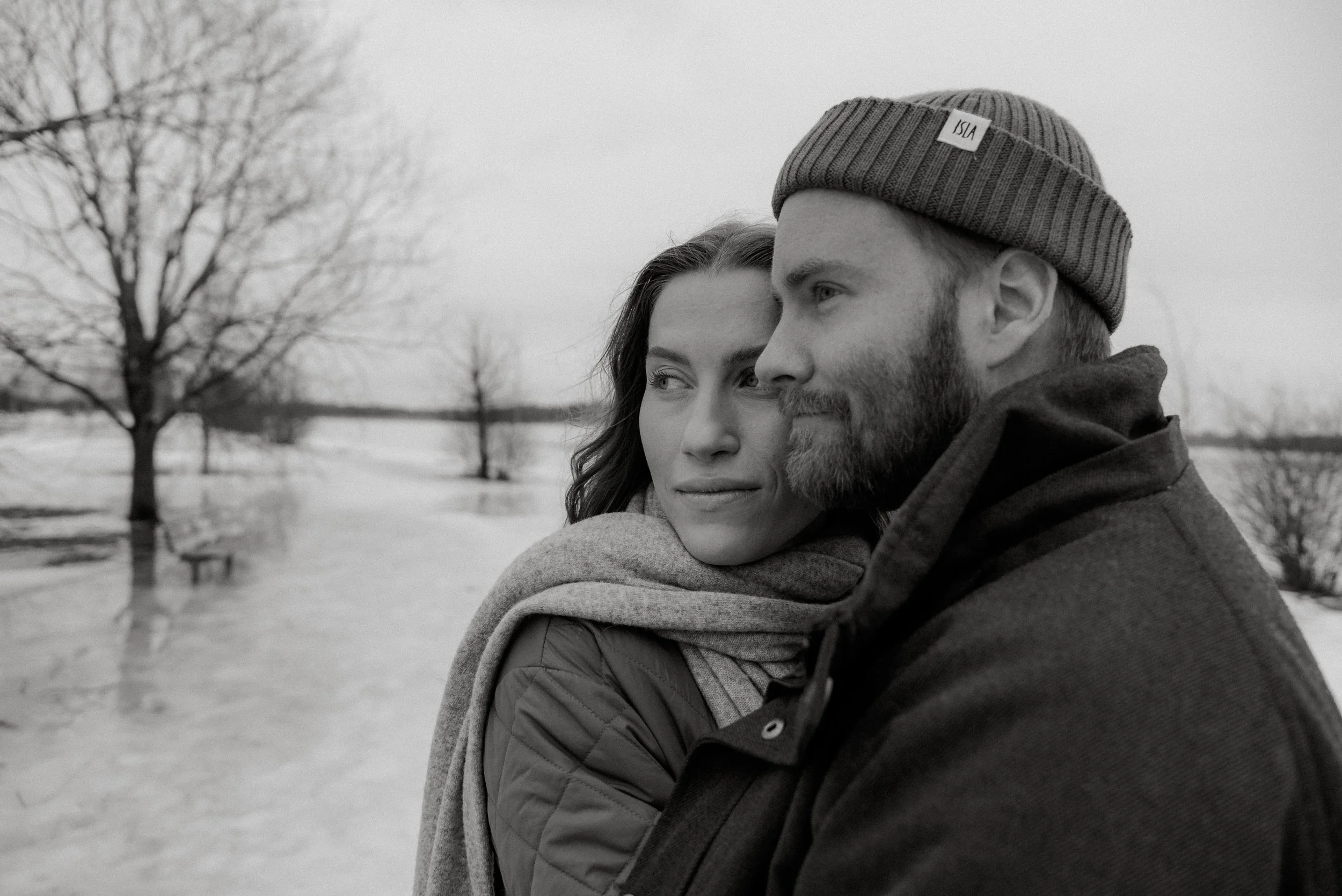 Mustavalkokuva, jossa pariskunta seisoo vierekkäin talvimaisemassa. Pariskuntakuvaus Helsinki. Valokuvaaja Heidi Väisänen.