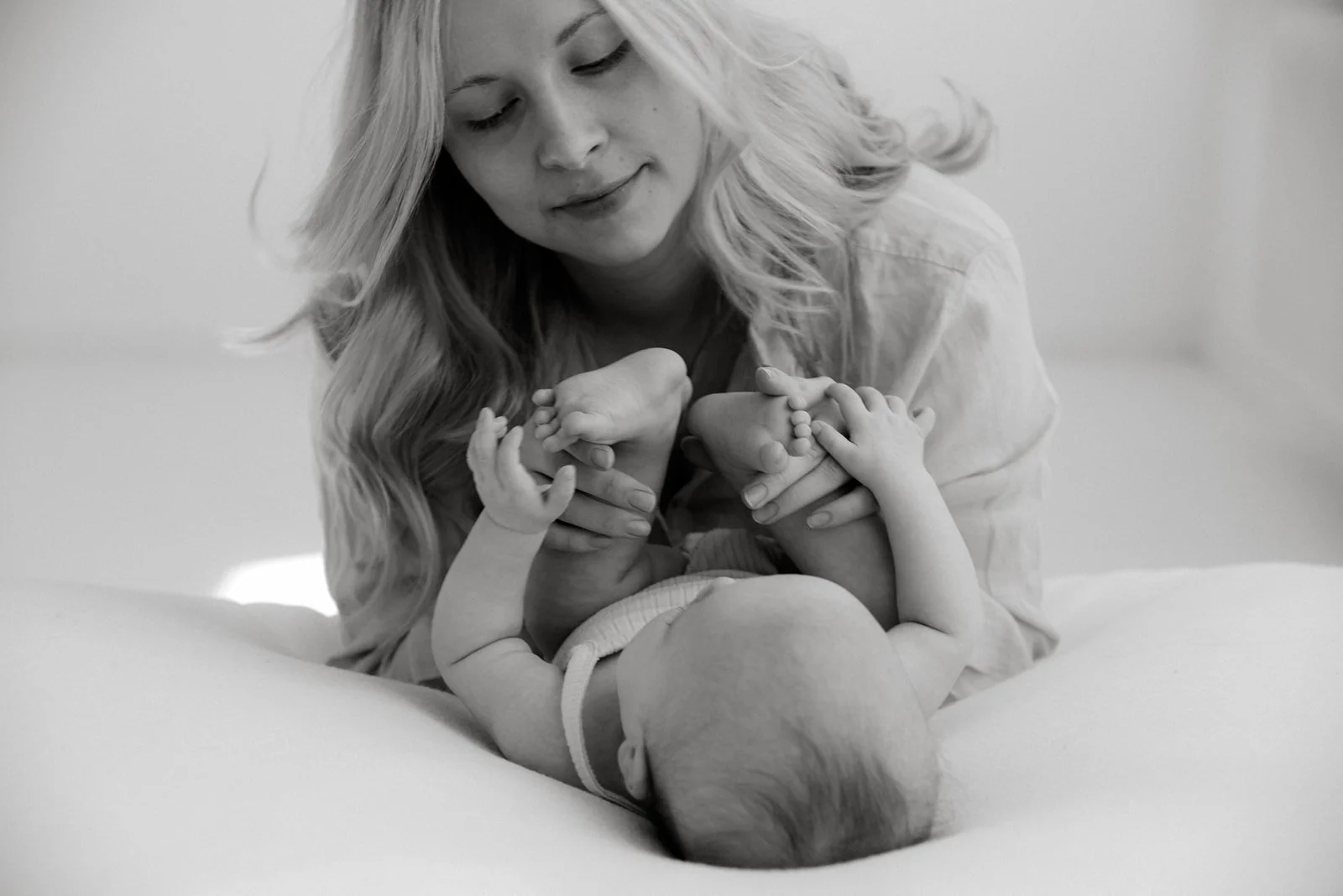 Äiti pitelee hellästi vauvansa jalkoja käsiensä välissä.