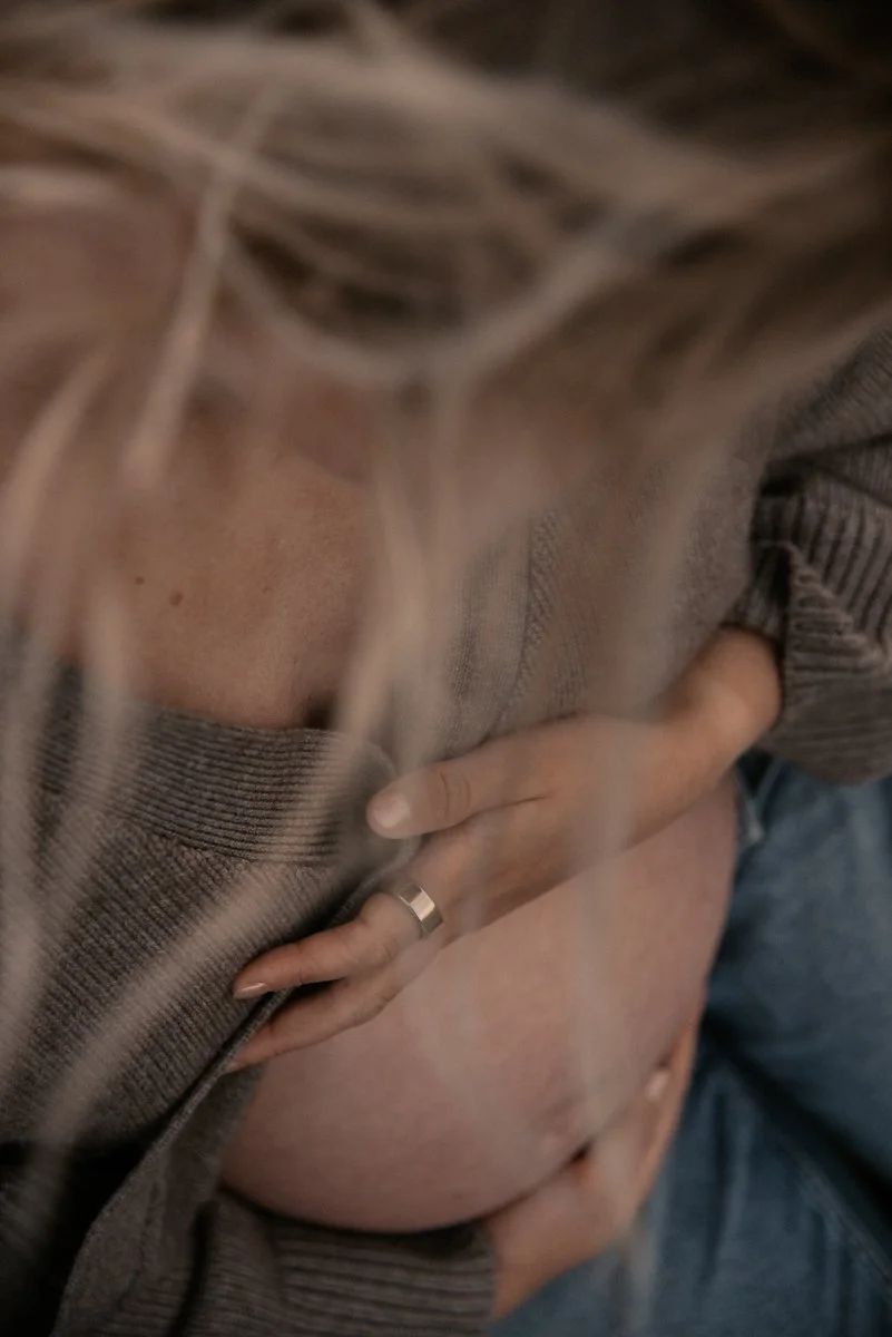 Äidin hellä kosketus raskausvatsaan. Odotusajankuvaus Helsinki.