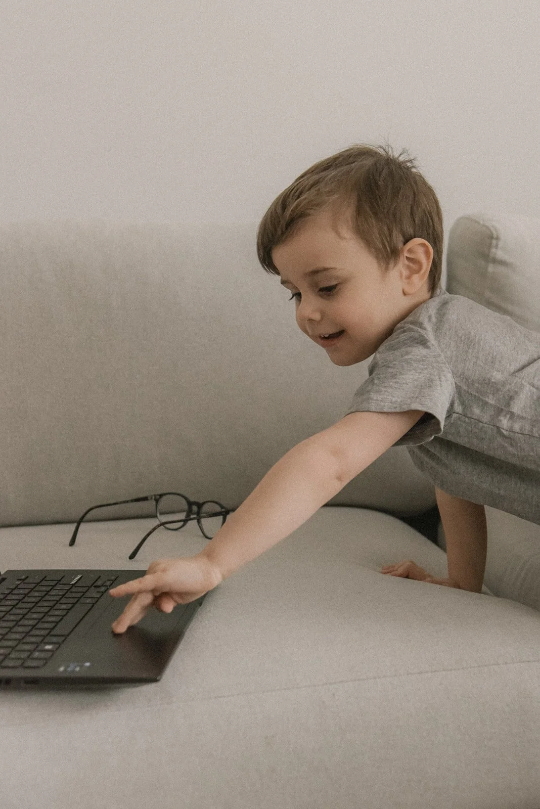 Lapsi koskettaa äidin tietokonetta. Perhekuvaus kotona.