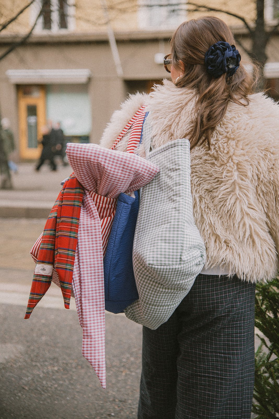 Tuotekuva Edlan laukuista. Yrittäjä kantaa olalla useita kasseja kaupunkimiljöössä.