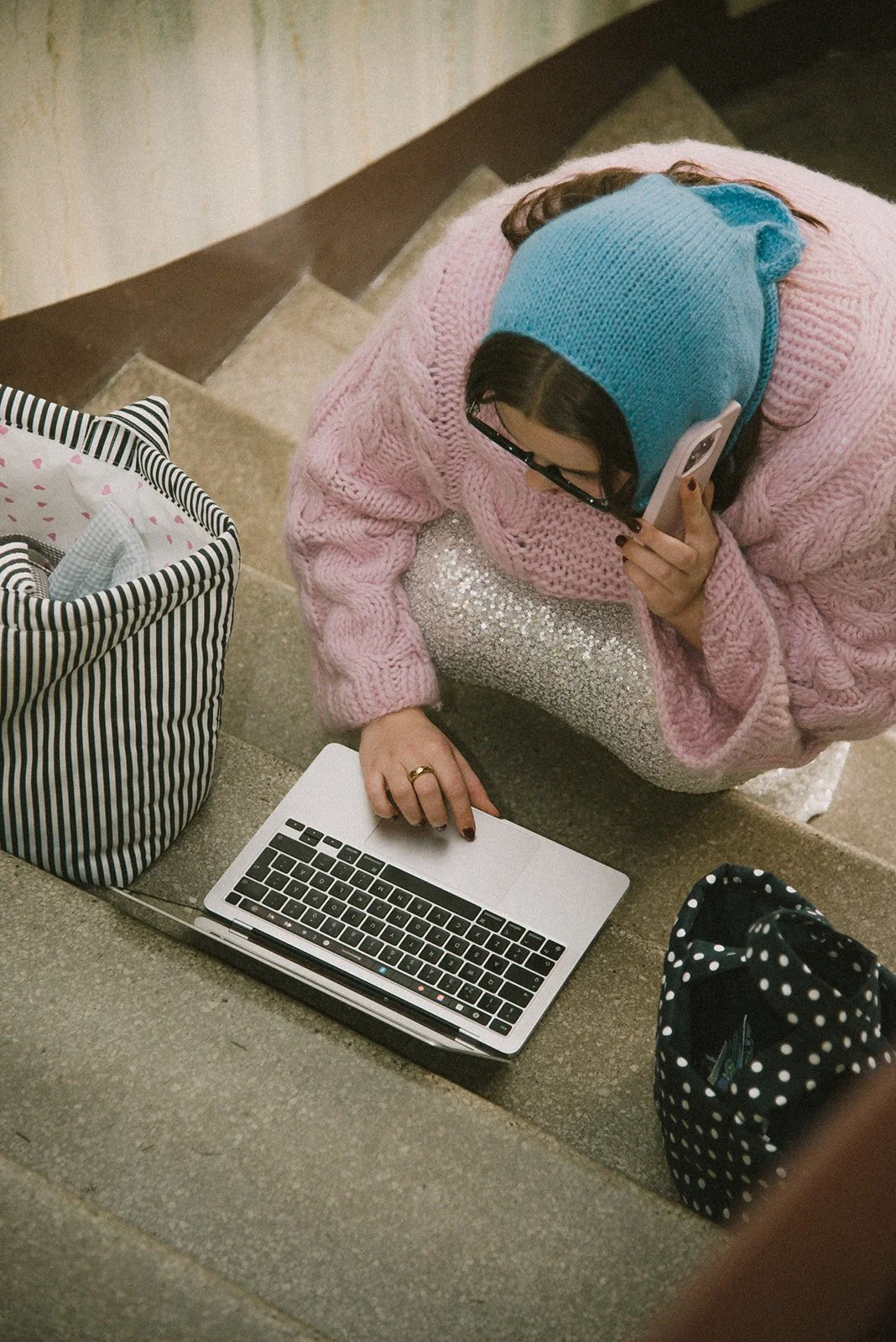 Edlan yrityskuvaus, yrittäjä näpyttelee tietokonetta portaikossa, vierellä brändin laukkuja.