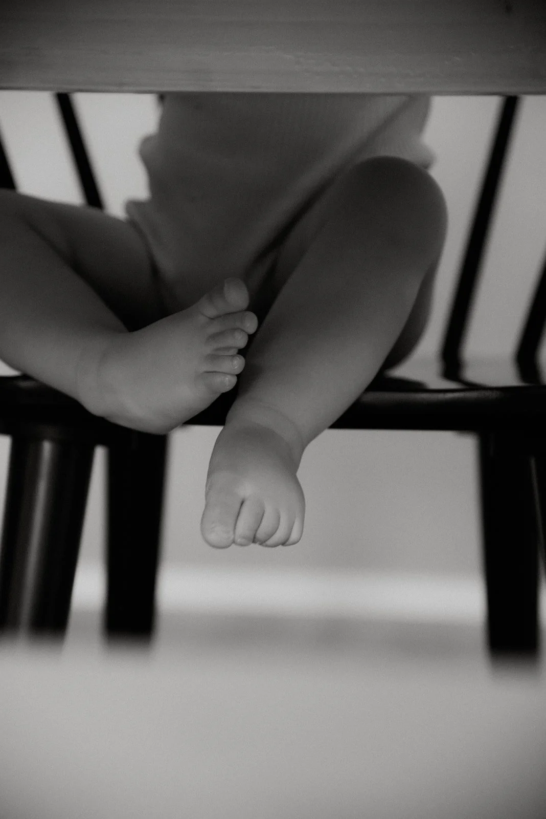 Tuolilla istuva vauva ja kippuraiset varpaat. Vauvakuvaus kotona.