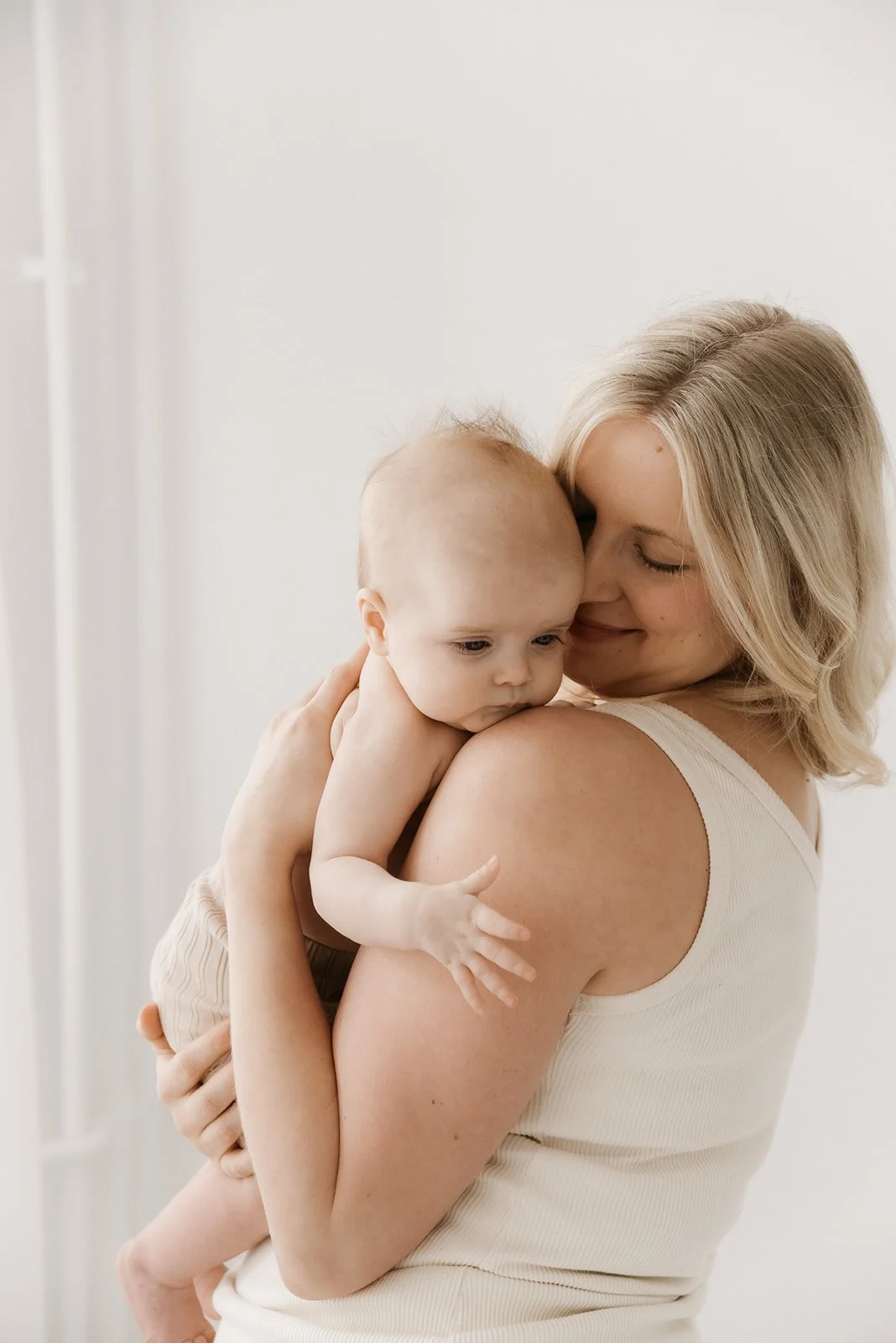 Äiti ja lapsi kuvattavana valoa tulvivassa studiossa.