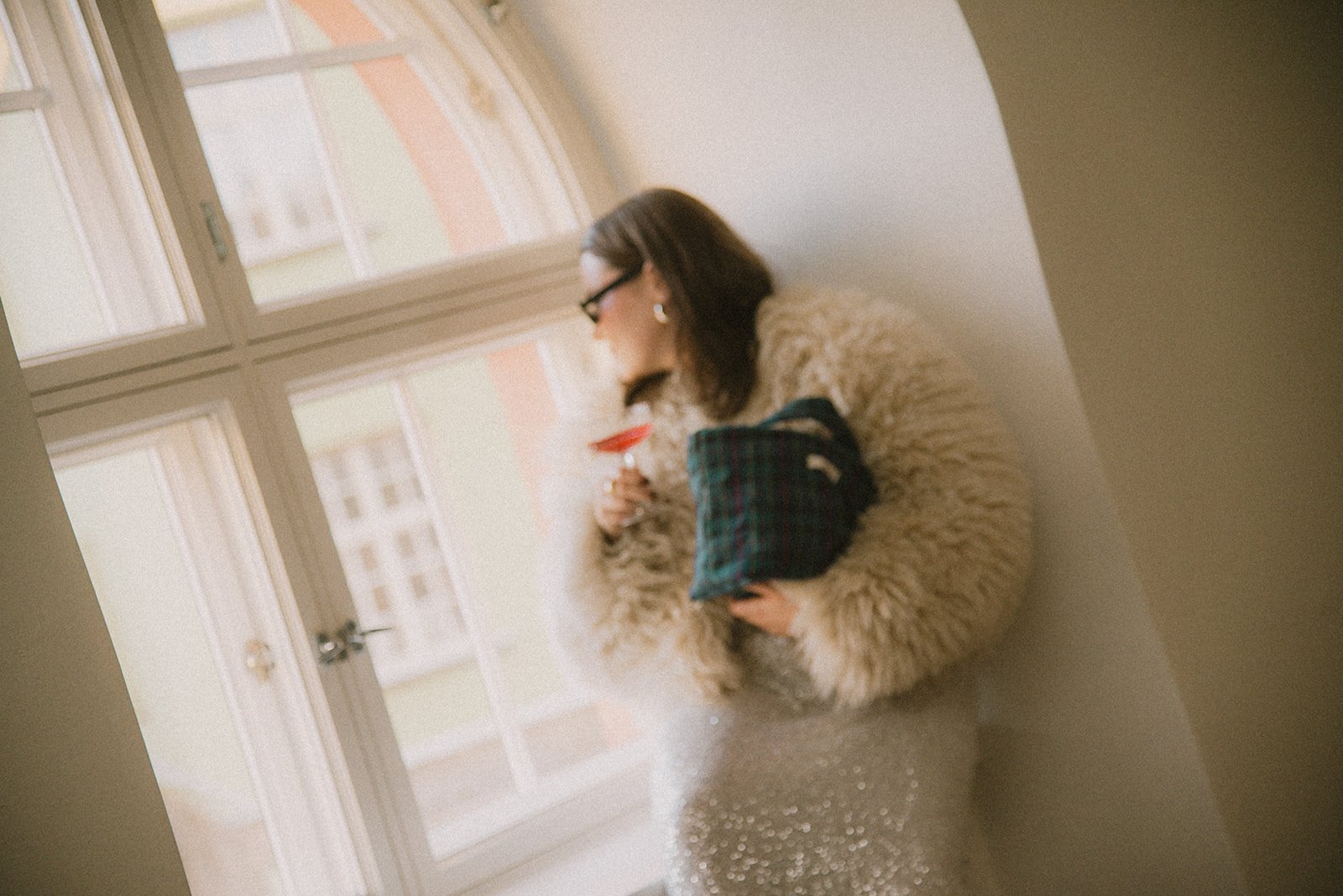 Edlan naisyrittäjä katsoo ikkunasta ulos lasi kädessä ja brändin laukku kainalossa. Brändikuvaus Helsinki.