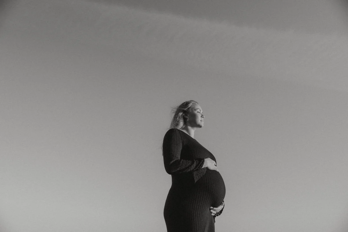 Nainen pitelee raskausvatsaansa mustavalkoisessa odotuskuvassa.