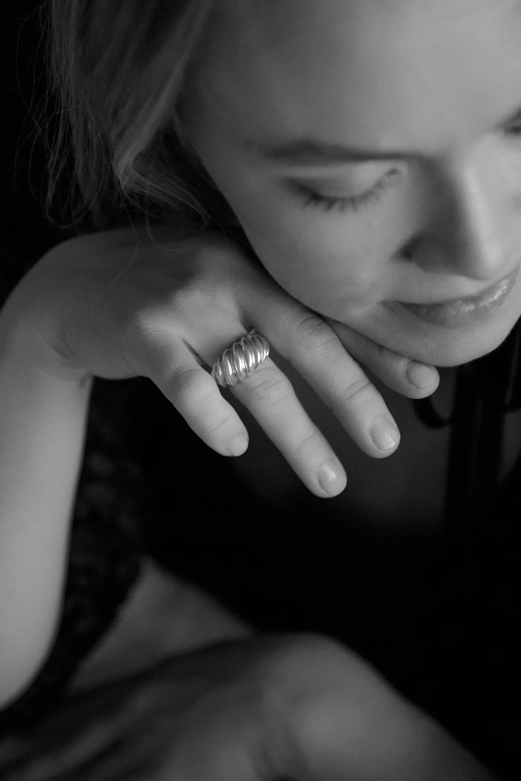 Mustavalkoinen tuotekuva, jossa nainen sormus kädessään.