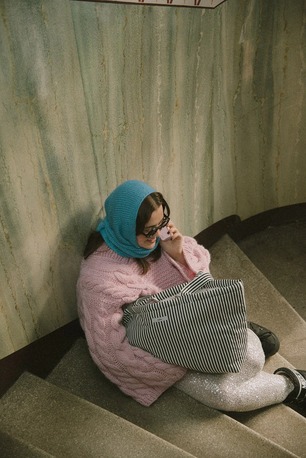 Edlan yrityskuvaukset Helsingissä, yrittäjä istuu portaikoissa brändin laukku kainalossaan.